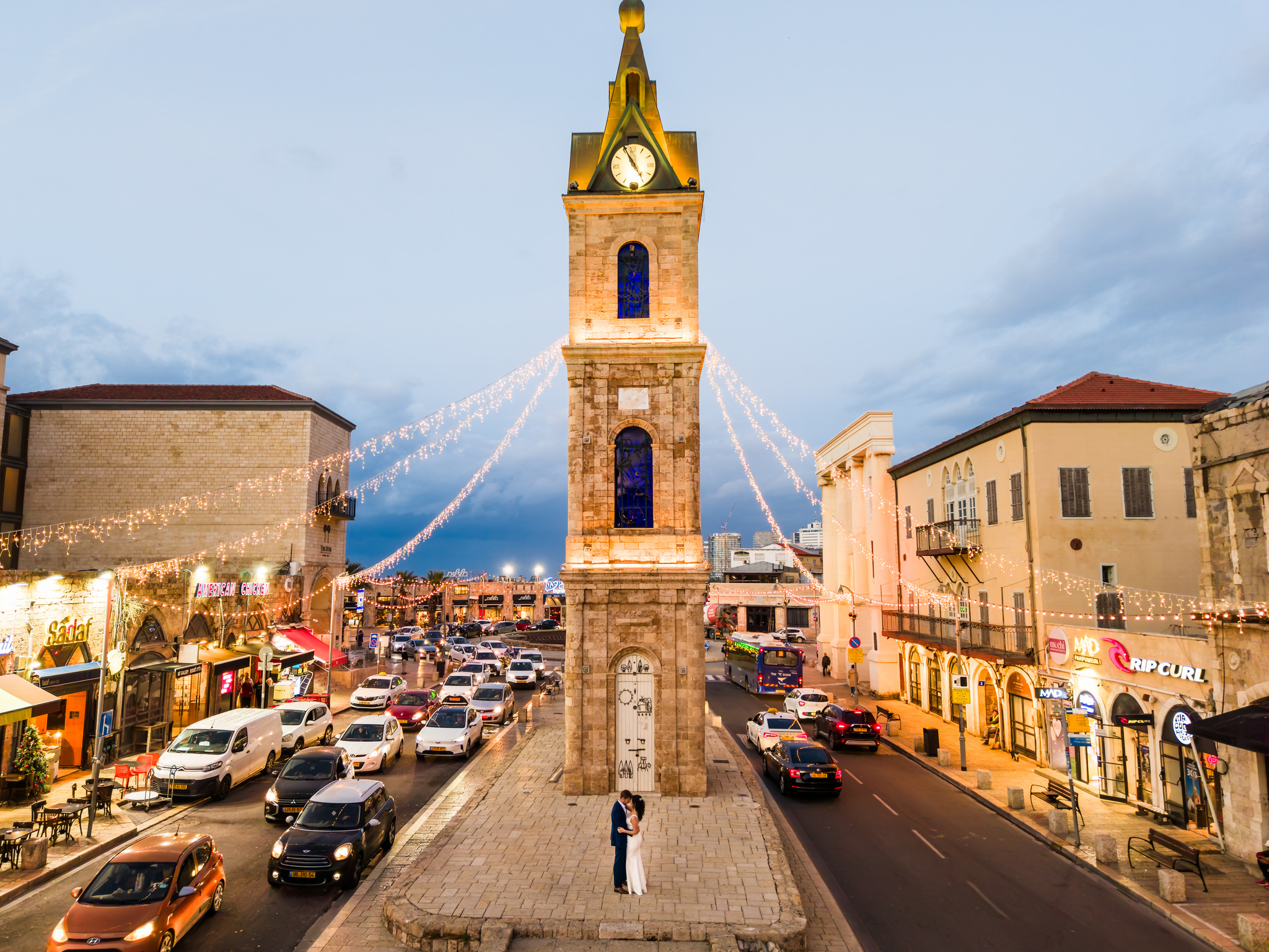 זוג מתחתן מחובק על מזח מעץ בזמן שקיעה